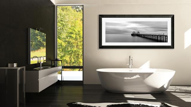 Panorama fine art framed of malibu pier black and white print on wall in bathroom as wall decor. bathtub and sink to the left by the window